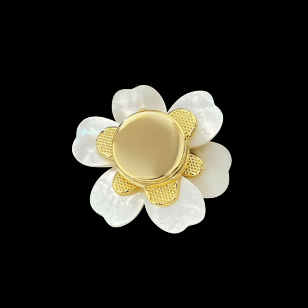 Gold and white flower-shaped brooch on a black background