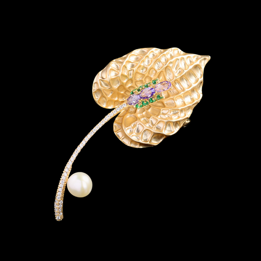 AVELIA textured gold calla lily brooch with purple crystal center and pearl accent on a curved stem.