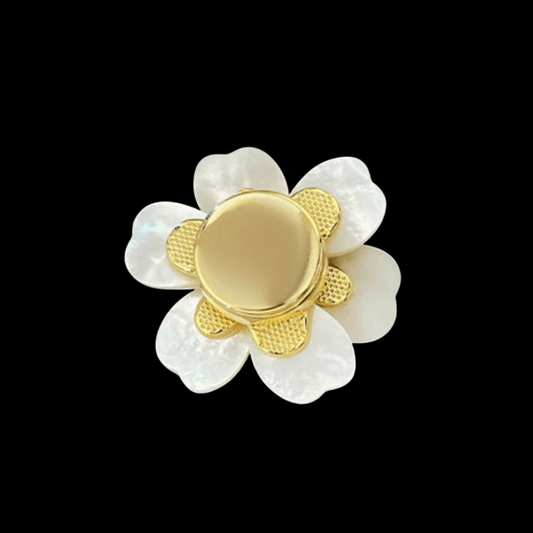 Gold and white flower-shaped brooch on a black background