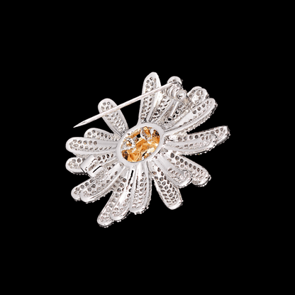 AVELIA silver sunflower brooch featuring fully paved crystal petals and a textured gold center on a black background.
